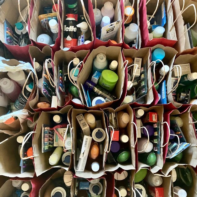bags filled with shampoo, conditioner, soap, toothpaste, toothbrushes, and more, ready to be distributed