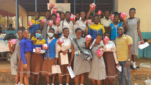 smiling women holding packages of sanitary pads at a high school in Tamale, Ghana