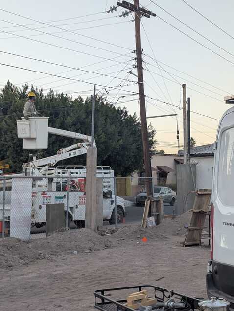 a crane with a bucket lifts a man towards a power line